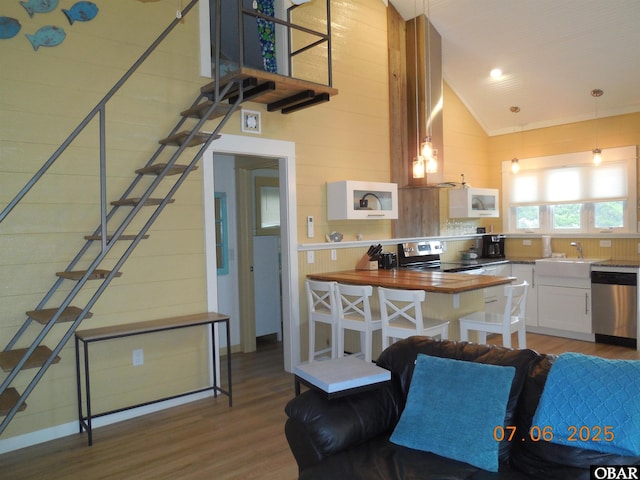 104 Sand Dollar Rd Lot # 23, Ocracoke, NC 27960 - kitchen with appliances with stainless steel finishes, wood finished floors, white cabinets, high vaulted ceiling, and wooden walls