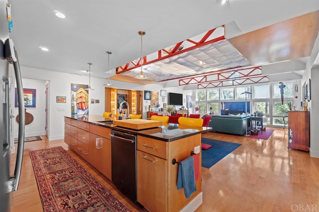 kitchen with a kitchen island with sink, a sink, open floor plan, appliances with stainless steel finishes, and light wood-type flooring