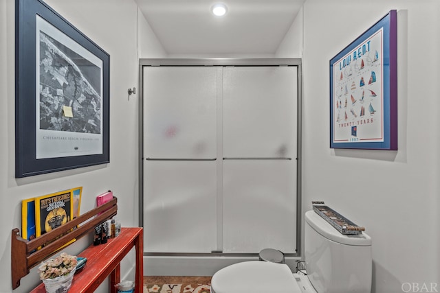 bathroom featuring a shower with shower door and toilet