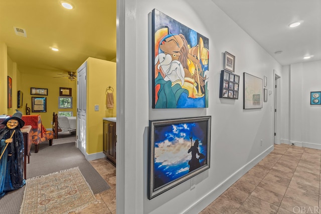 hallway with baseboards, visible vents, and recessed lighting