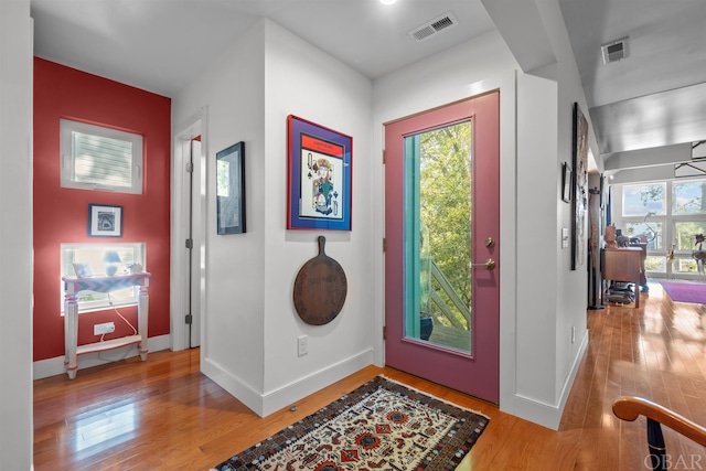 foyer featuring baseboards, visible vents, and wood finished floors