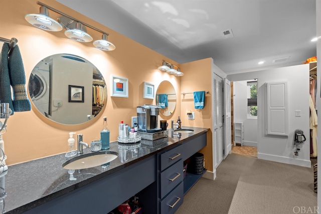 bathroom with a walk in closet, a sink, baseboards, and double vanity