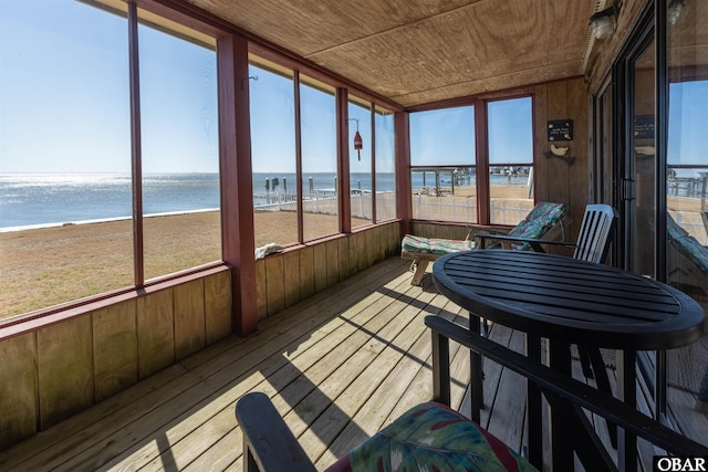 sunroom featuring a water view and wooden ceiling