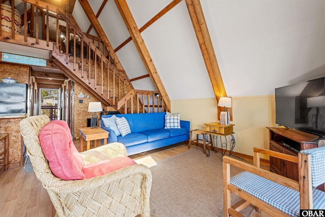 living area with beam ceiling, stairway, wood finished floors, and high vaulted ceiling