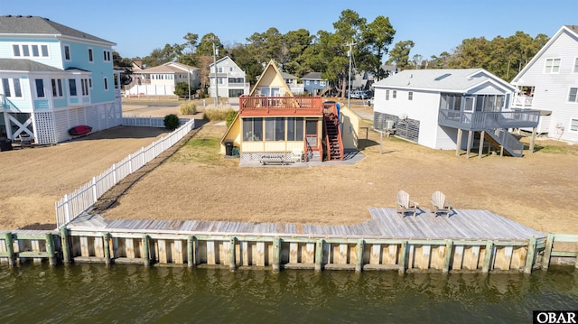 rear view of house featuring stairway, a deck with water view, a residential view, and a sunroom