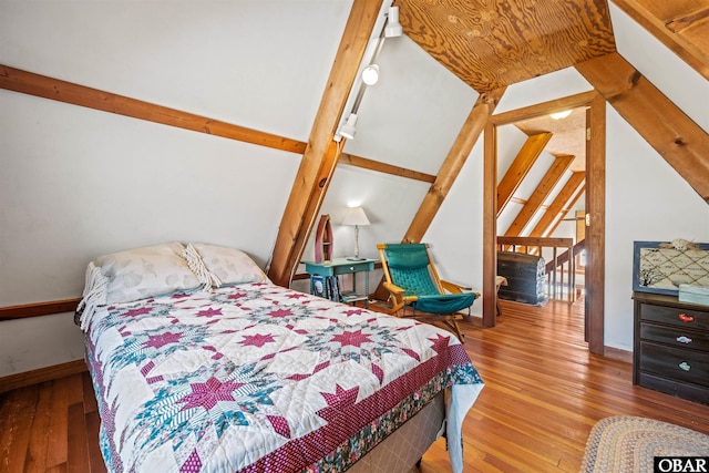 bedroom with lofted ceiling with beams, baseboards, and hardwood / wood-style flooring