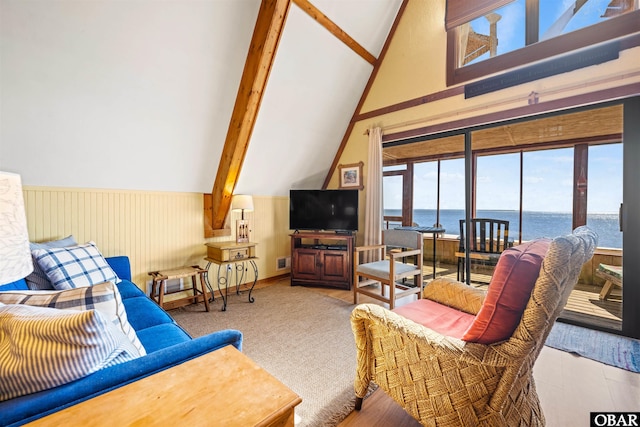 living area featuring a wainscoted wall and vaulted ceiling with beams