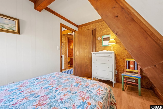 bedroom featuring wood finished floors and vaulted ceiling with beams