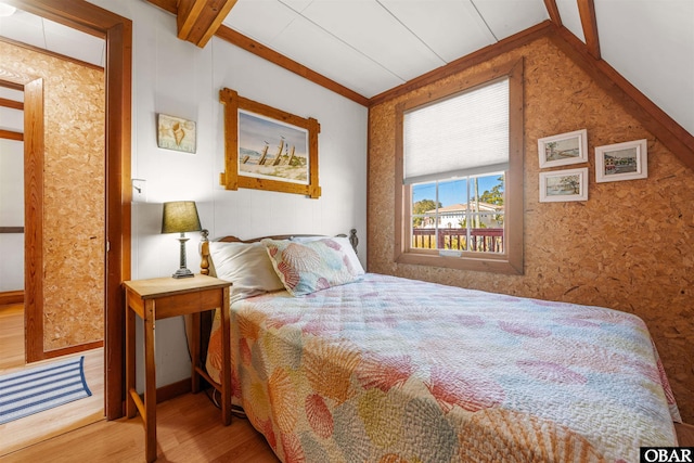 bedroom with beamed ceiling and wood finished floors