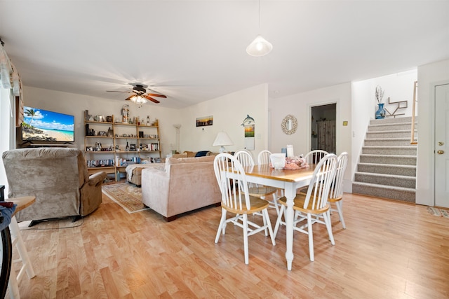 dining room featuring stairway, light wood-style flooring, and a ceiling fan