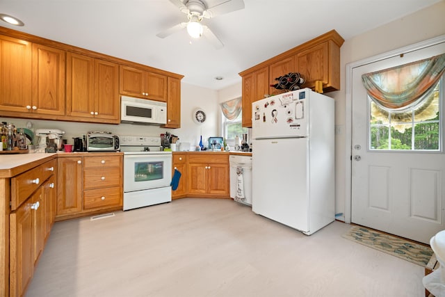 kitchen with light wood finished floors, light countertops, white appliances, and brown cabinetry