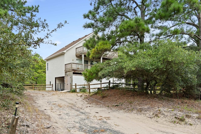 view of side of home featuring dirt driveway and fence