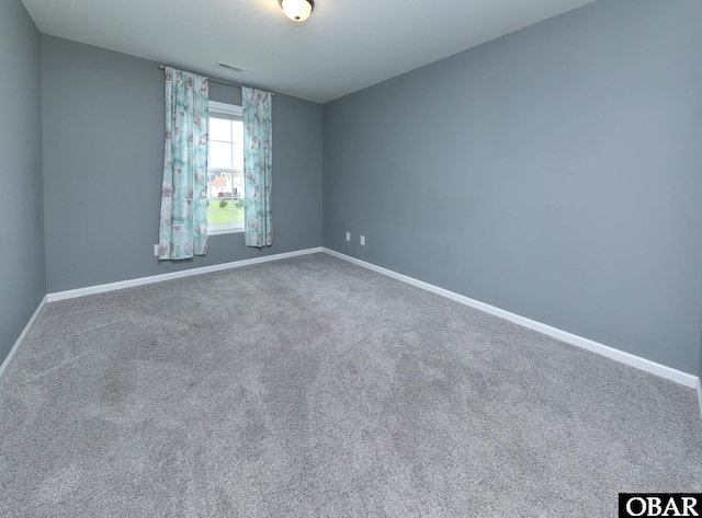 unfurnished room with carpet floors, visible vents, and baseboards