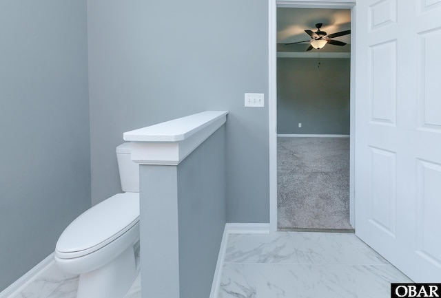 half bath with baseboards, a ceiling fan, marble finish floor, and toilet