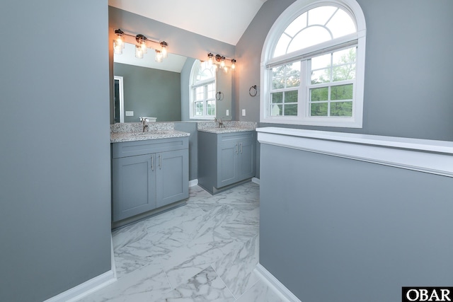 bathroom featuring two vanities, vaulted ceiling, marble finish floor, and a sink