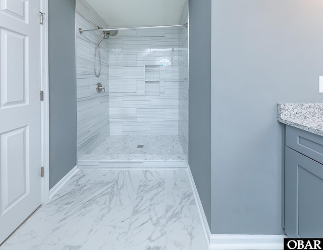 full bathroom with a tile shower, baseboards, marble finish floor, and vanity