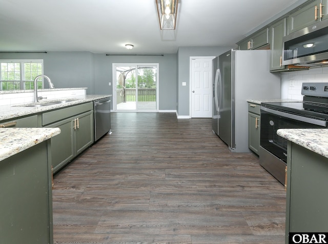kitchen featuring dark wood finished floors, baseboards, appliances with stainless steel finishes, and a sink