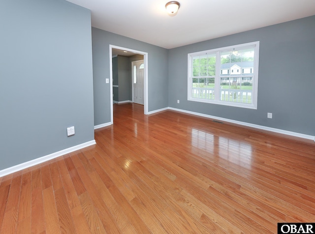 unfurnished room with light wood finished floors, baseboards, and visible vents