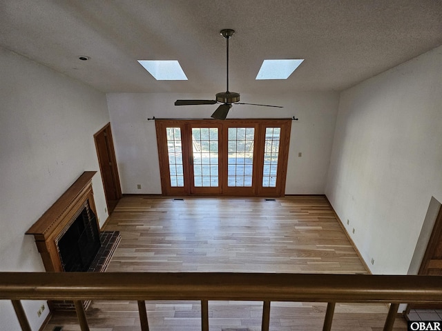 unfurnished living room with light wood-style floors, lofted ceiling, ceiling fan, and a textured ceiling