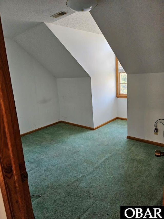 additional living space with baseboards, visible vents, lofted ceiling, a textured ceiling, and carpet floors