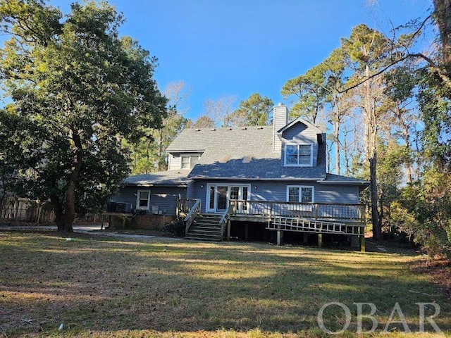 rear view of property featuring a yard, a chimney, and a wooden deck