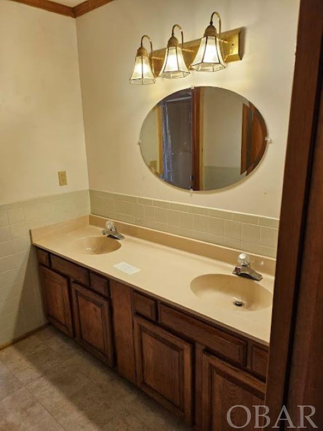 bathroom with a wainscoted wall, a sink, tile walls, and double vanity