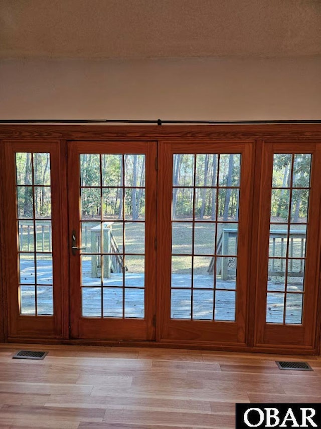 doorway to outside with light wood-style floors, visible vents, and a textured ceiling