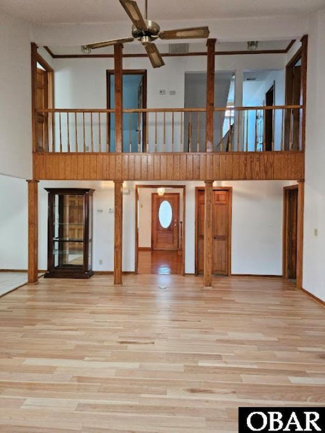 unfurnished living room featuring light wood-style flooring, a high ceiling, and ceiling fan