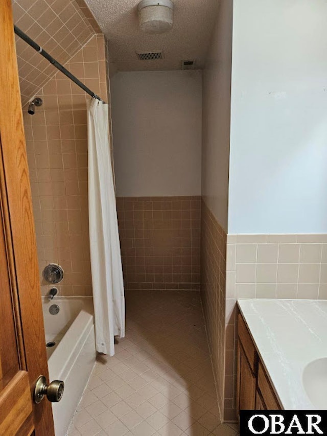 full bath featuring tile walls, visible vents, shower / bathtub combination with curtain, a textured ceiling, and tile patterned flooring