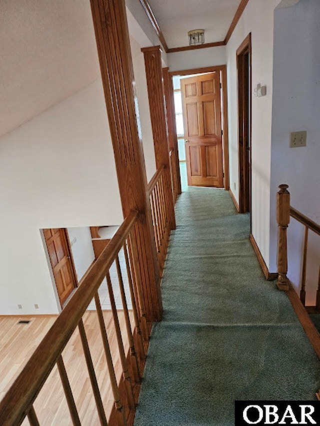 hallway featuring visible vents, baseboards, an upstairs landing, carpet, and crown molding