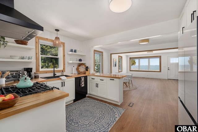 kitchen with open shelves, a sink, butcher block countertops, black dishwasher, and exhaust hood