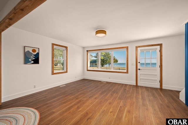 unfurnished room featuring dark wood finished floors, visible vents, and baseboards
