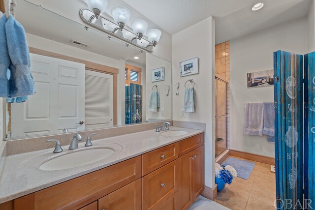 full bath featuring tile patterned flooring, a sink, visible vents, and a shower stall