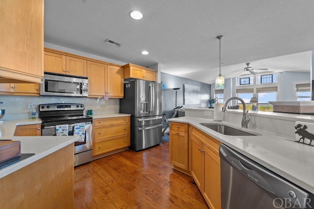 kitchen with decorative light fixtures, stainless steel appliances, visible vents, light countertops, and a sink