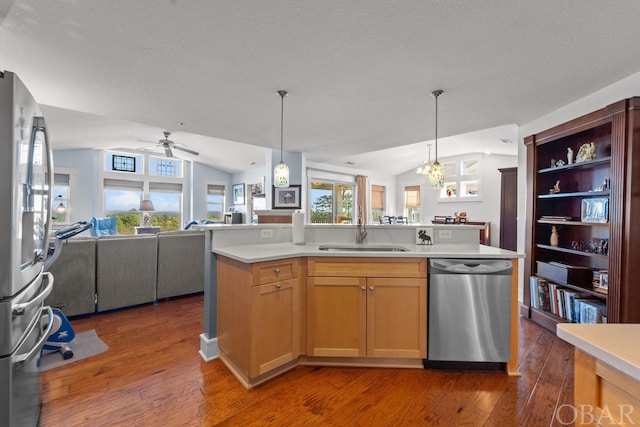 kitchen featuring a center island with sink, stainless steel appliances, light countertops, open floor plan, and a sink