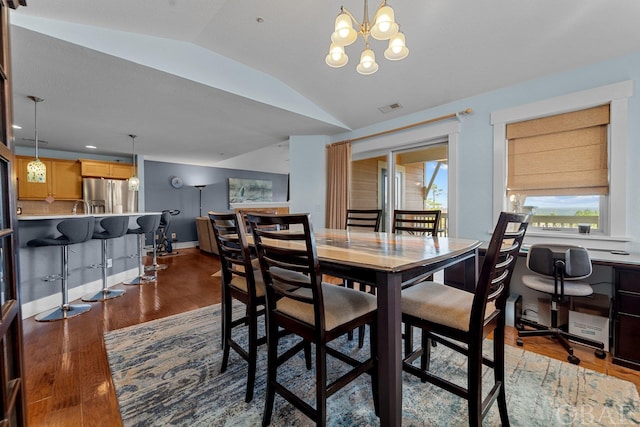 dining space with baseboards, visible vents, lofted ceiling, wood finished floors, and an inviting chandelier