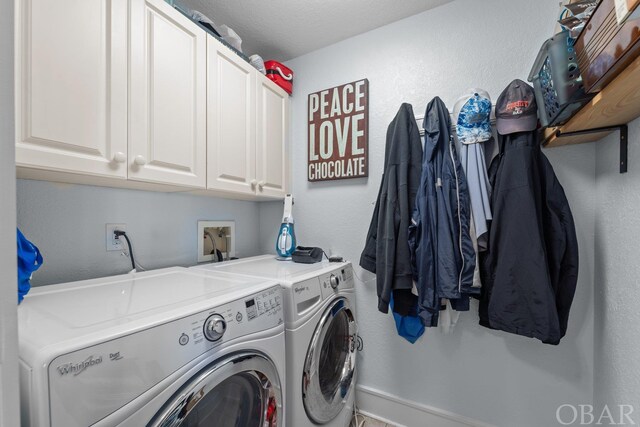 washroom featuring cabinet space, a textured wall, and washing machine and clothes dryer