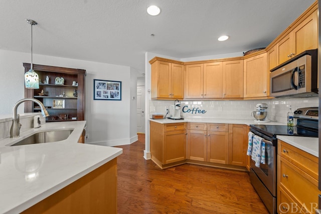 kitchen with stainless steel appliances, a sink, light countertops, and decorative light fixtures