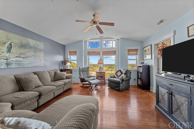 living area featuring vaulted ceiling, wood finished floors, visible vents, and baseboards