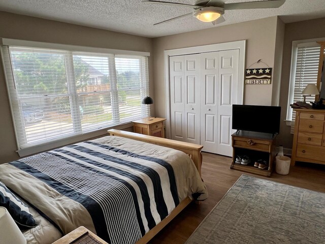 bedroom featuring a textured ceiling, dark wood-type flooring, a closet, and a ceiling fan