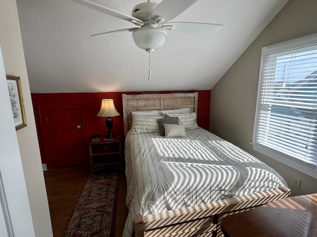 bedroom with lofted ceiling, dark wood-style flooring, a textured ceiling, and a ceiling fan