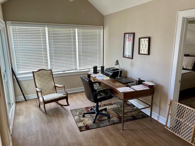 home office featuring lofted ceiling, baseboards, and wood finished floors