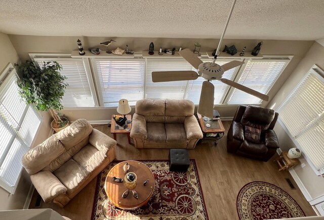 living area with a textured ceiling, baseboards, and wood finished floors