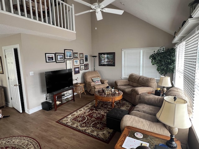 living room with high vaulted ceiling, ceiling fan, baseboards, and wood finished floors