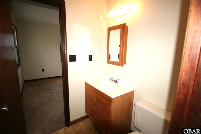 half bath featuring toilet, vanity, and baseboards