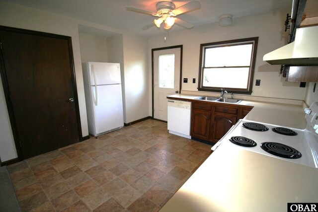 kitchen with light countertops, stone finish flooring, a sink, white appliances, and under cabinet range hood