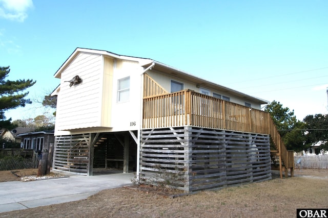 view of property exterior with a carport, concrete driveway, and stairs