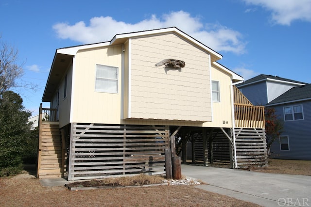 view of front of property with stairs, a carport, and concrete driveway