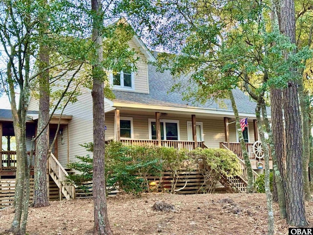 view of front facade featuring roof with shingles, a porch, and stairway