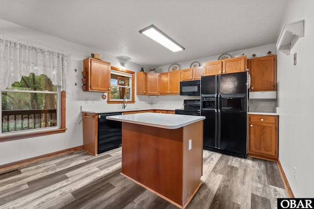 kitchen featuring a sink, visible vents, light countertops, a center island, and black appliances